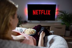 Frau auf Couch schaut Netflix